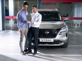 A customer and a Nissan service advisor standing in front of a Qashqai